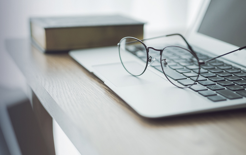 室内の明るい窓際のイメージ画像。カーテン越しの光とPC、眼鏡が置かれています