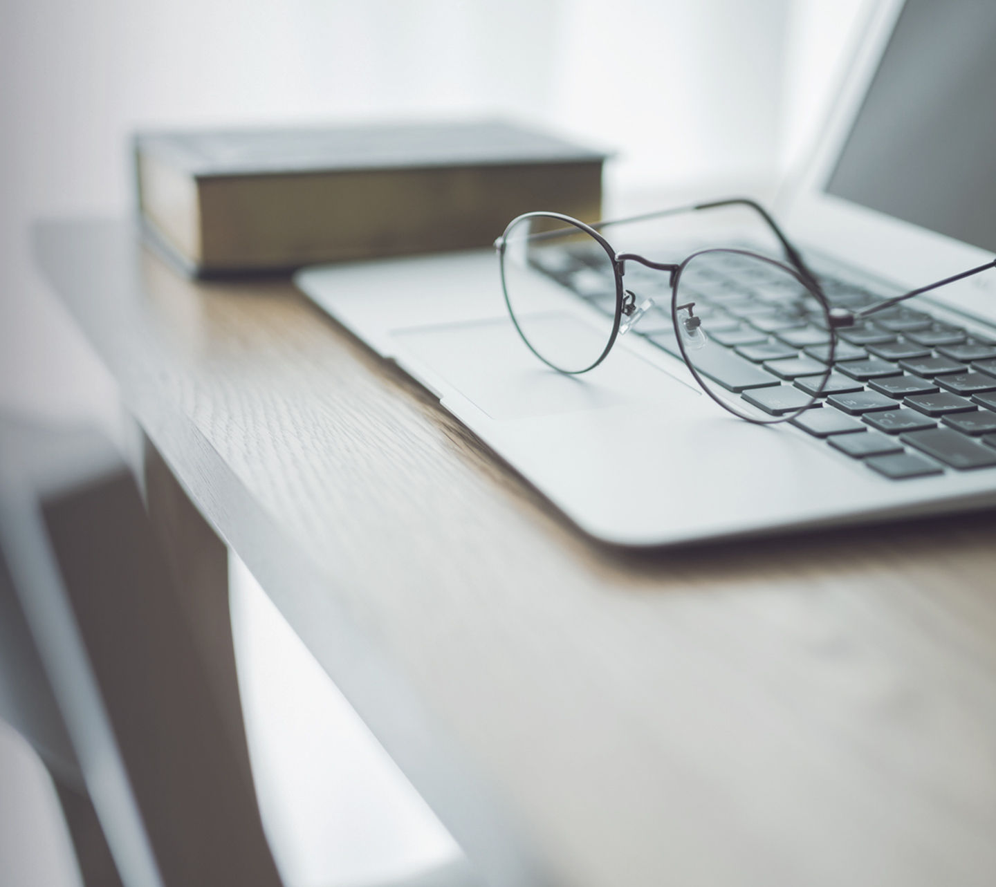 室内の明るい窓際のイメージ画像。カーテン越しの光とPC、眼鏡が置かれています